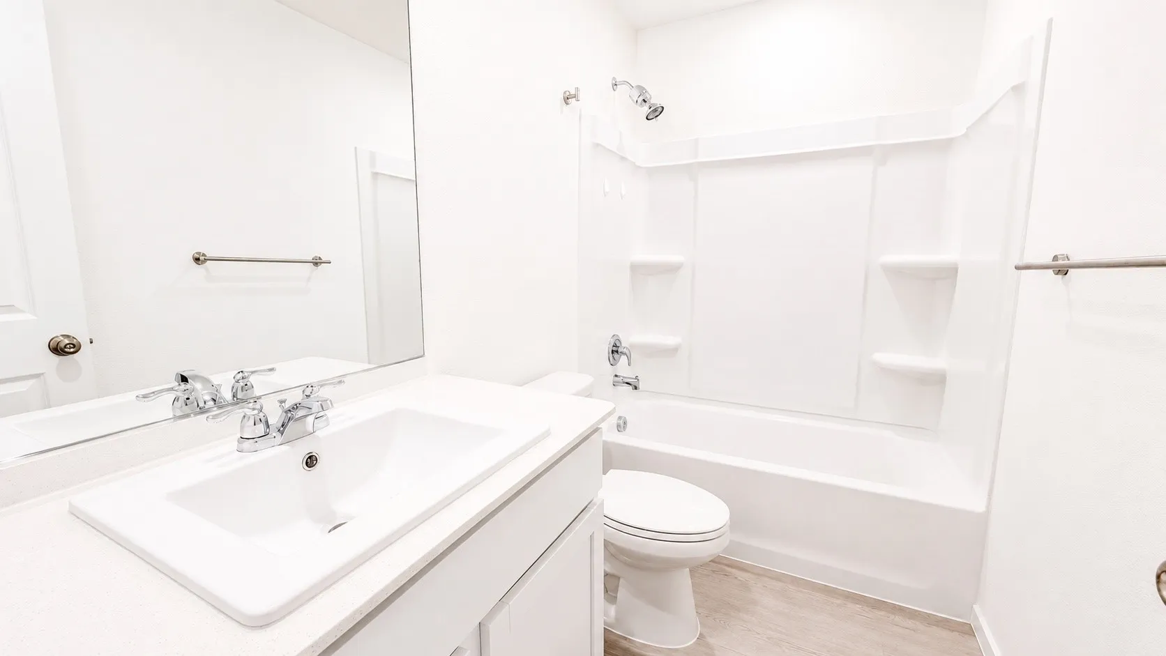 White bathroom featuring a single vanity with chrome fixtures, a rectangular undermount sink, and a white countertop