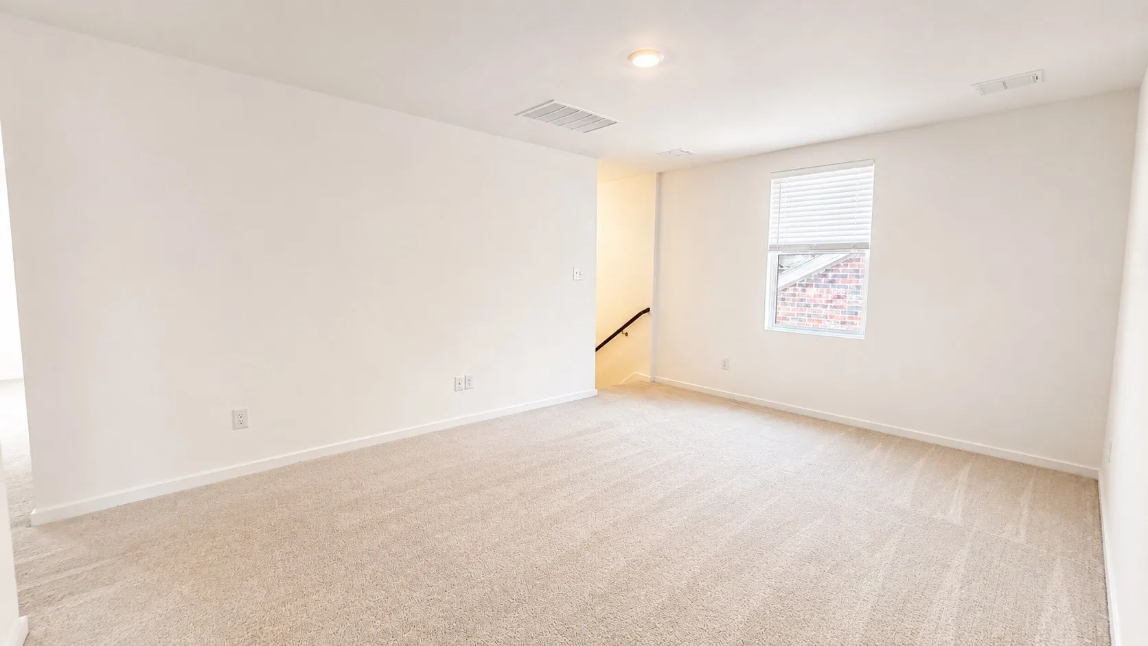 Spacious room with plush carpeting, neutral wall finishes, and a single window with blinds