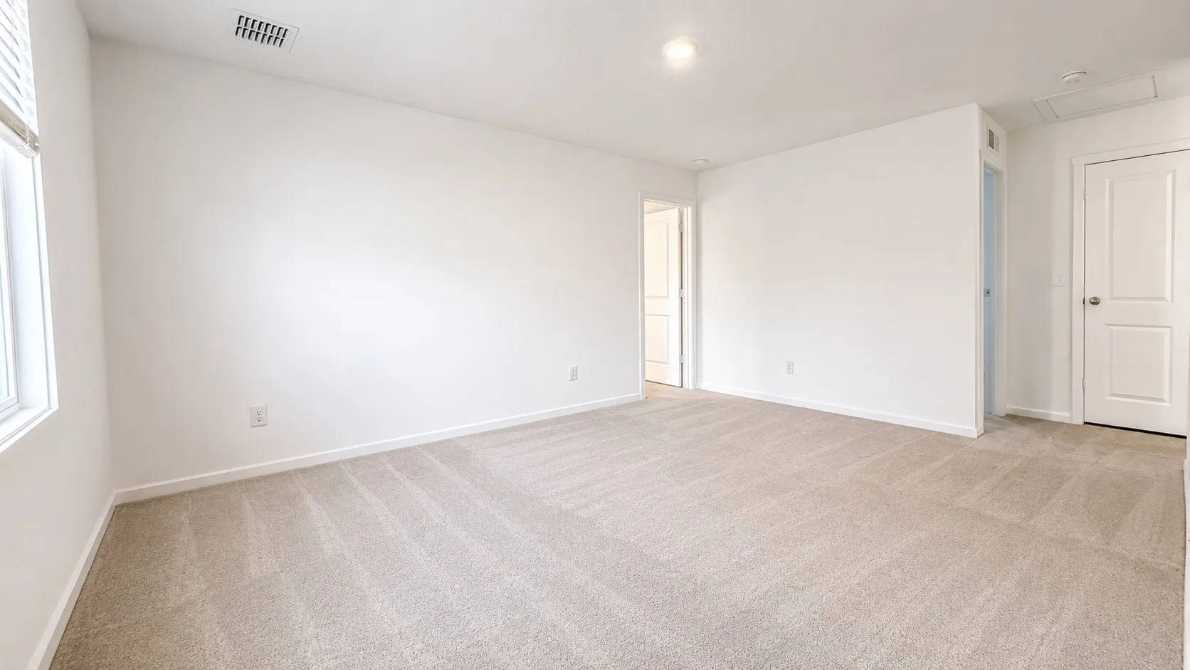 Neutral tone wall finish with light beige carpeting, white trim, and recessed ceiling lighting