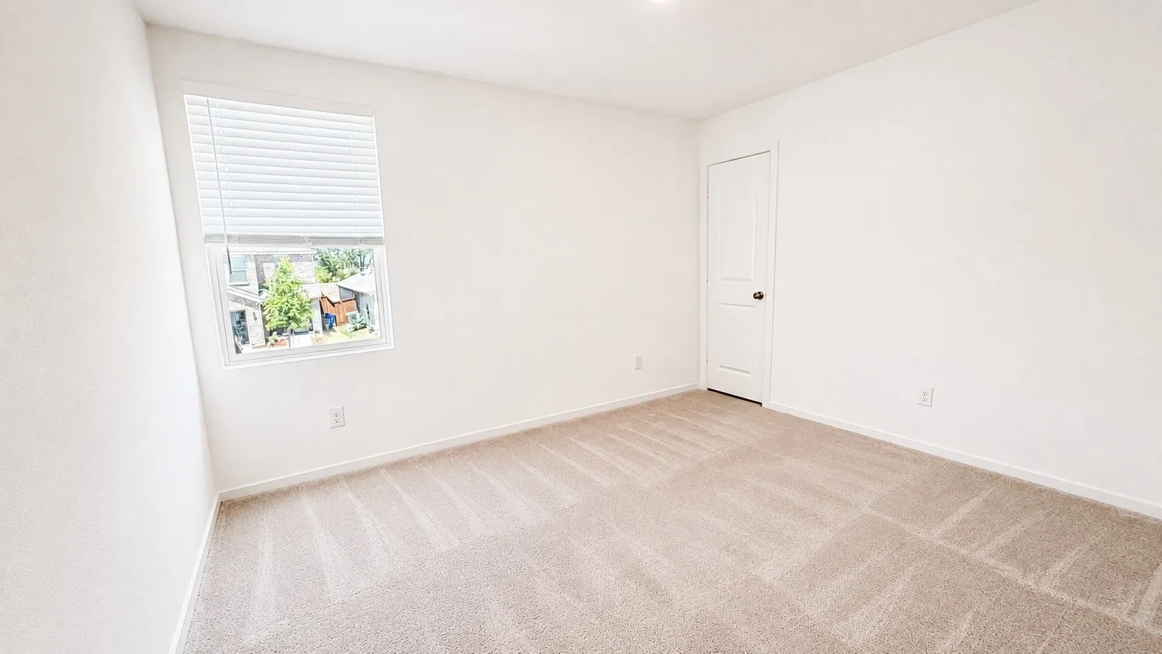 Neutral-toned carpet flooring, white walls, and a white interior door with dark hardware
