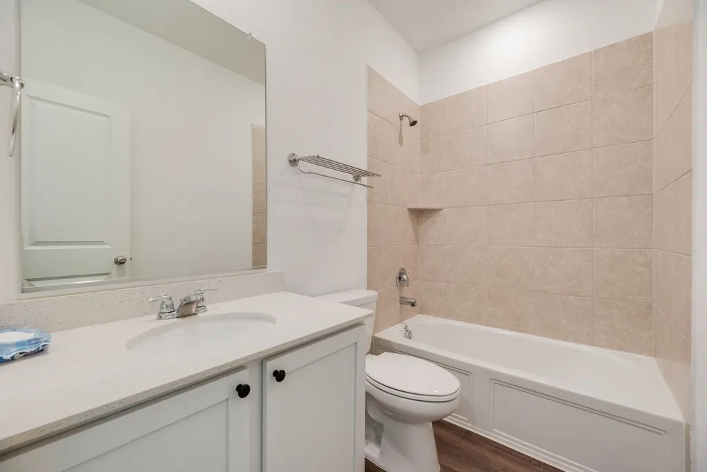 Bathroom featuring a white bathtub with a tiled surround, a built-in shower niche, and a chrome shower head and fixtures