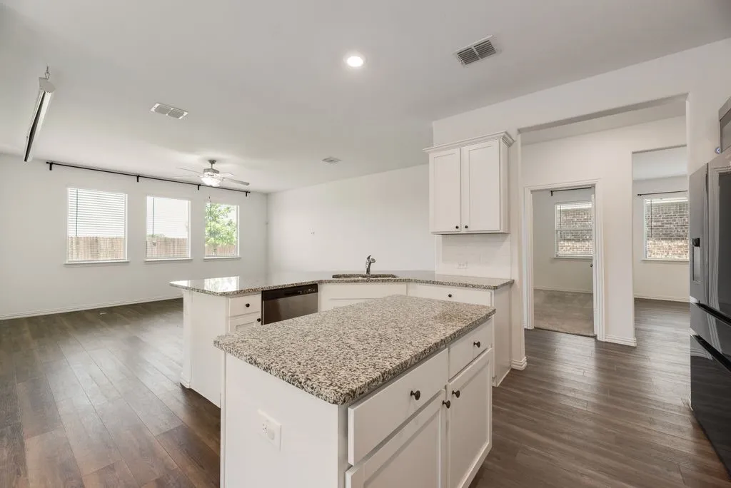 Kitchen featuring white cabinetry, light-toned speckled countertops, and a built-in dishwasher