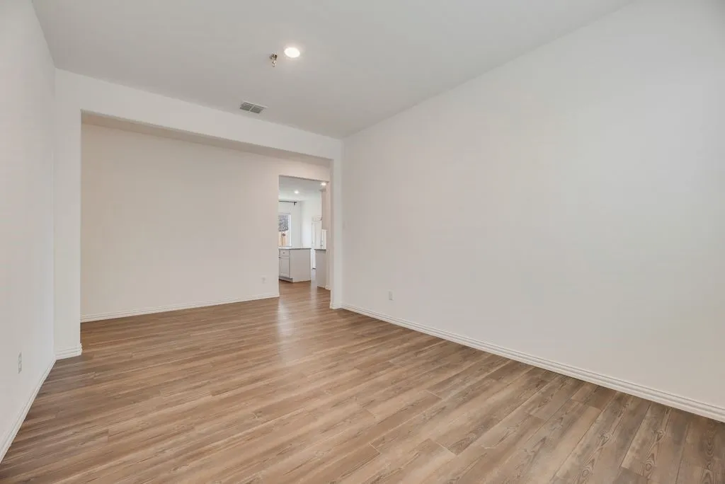 Spacious interior room featuring wood-finish flooring, recessed lighting, and a neutral color palette