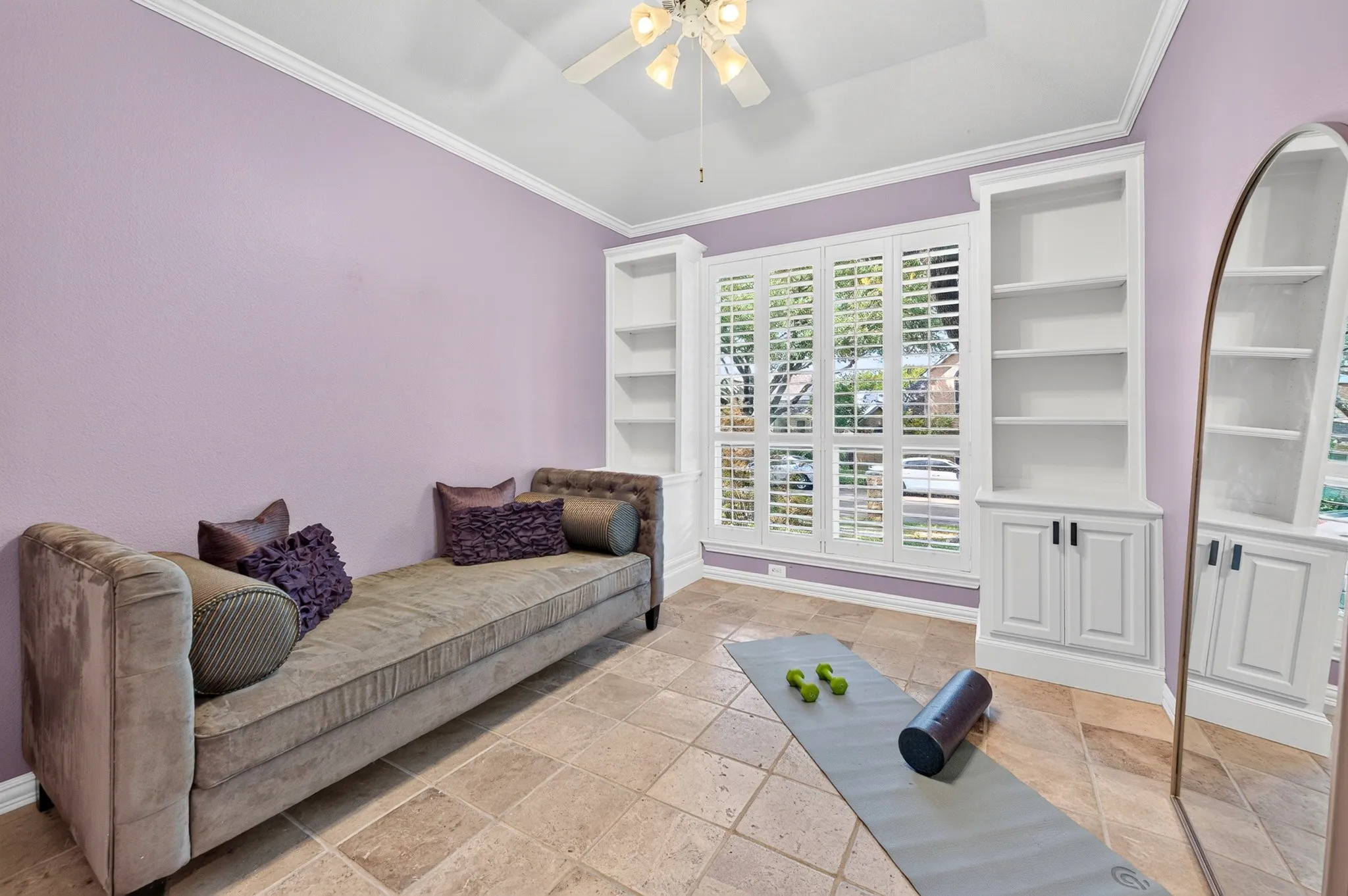 Built-in shelving units, extensive window with plantation shutters, tile flooring, and crown molding