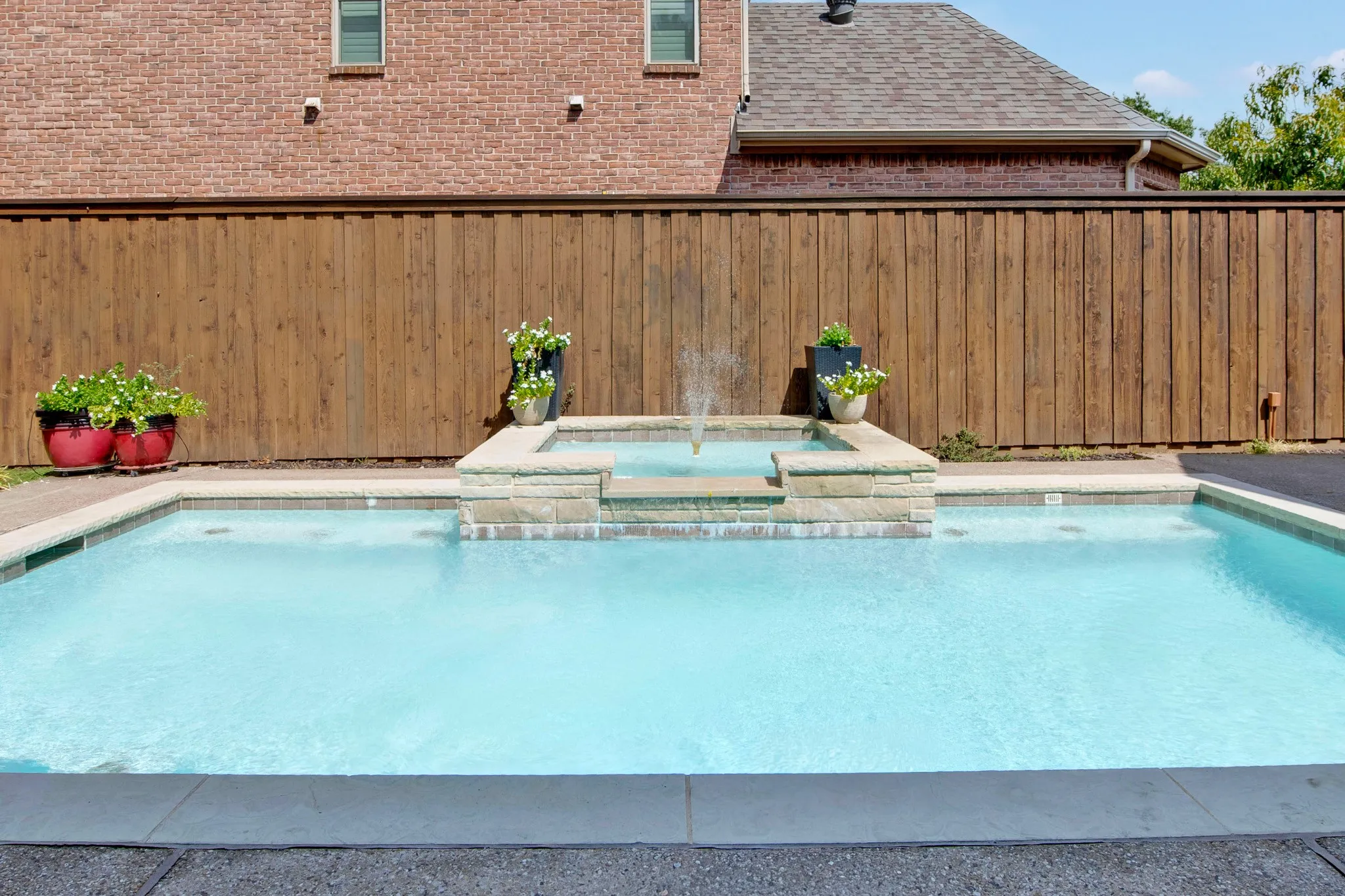 Swimming pool with a built-in spa featuring a stone-clad surround and water fountain