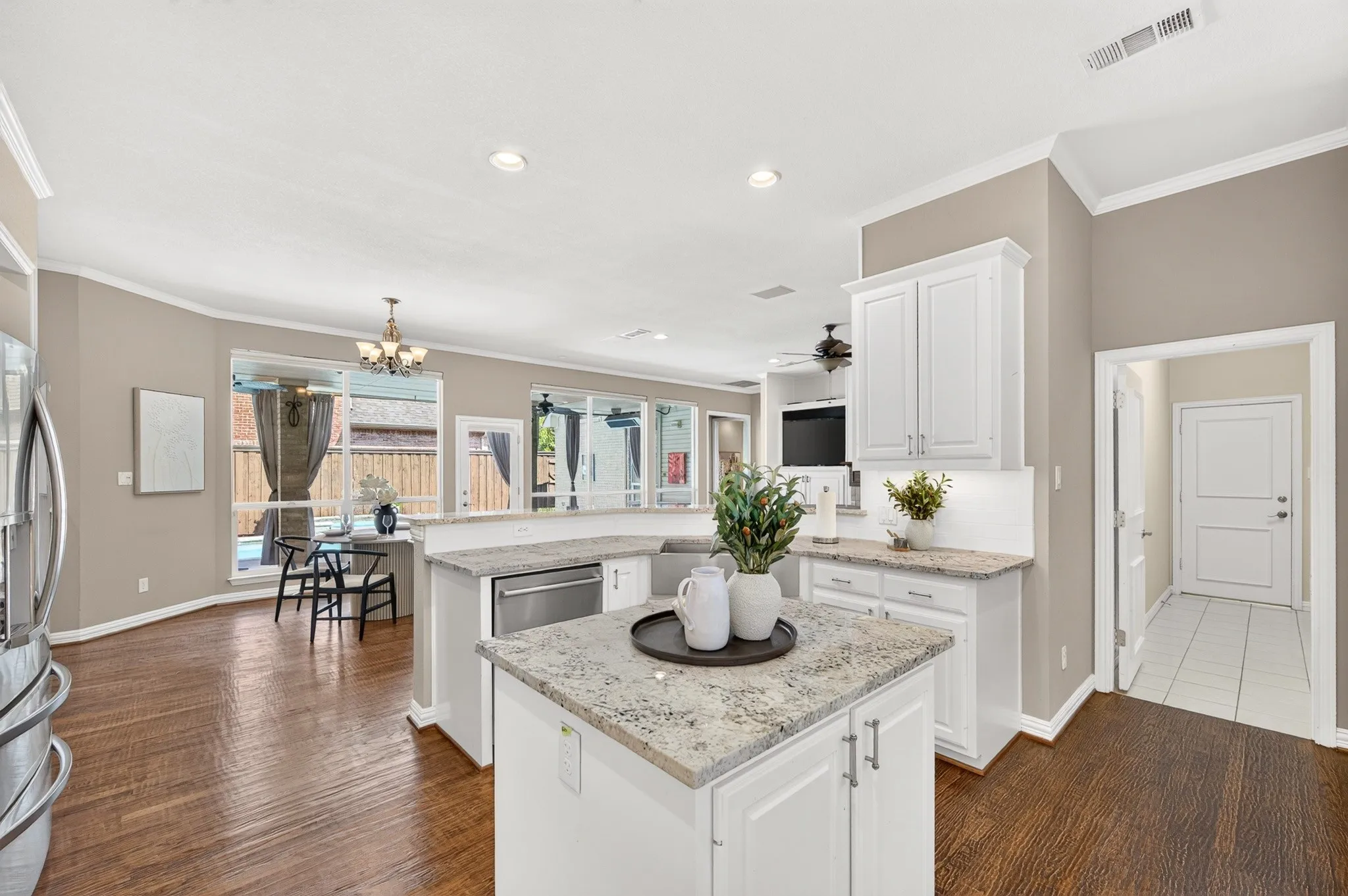 Kitchen featuring white cabinetry, light-toned countertops, a stainless steel dishwasher, and wood-finish flooring