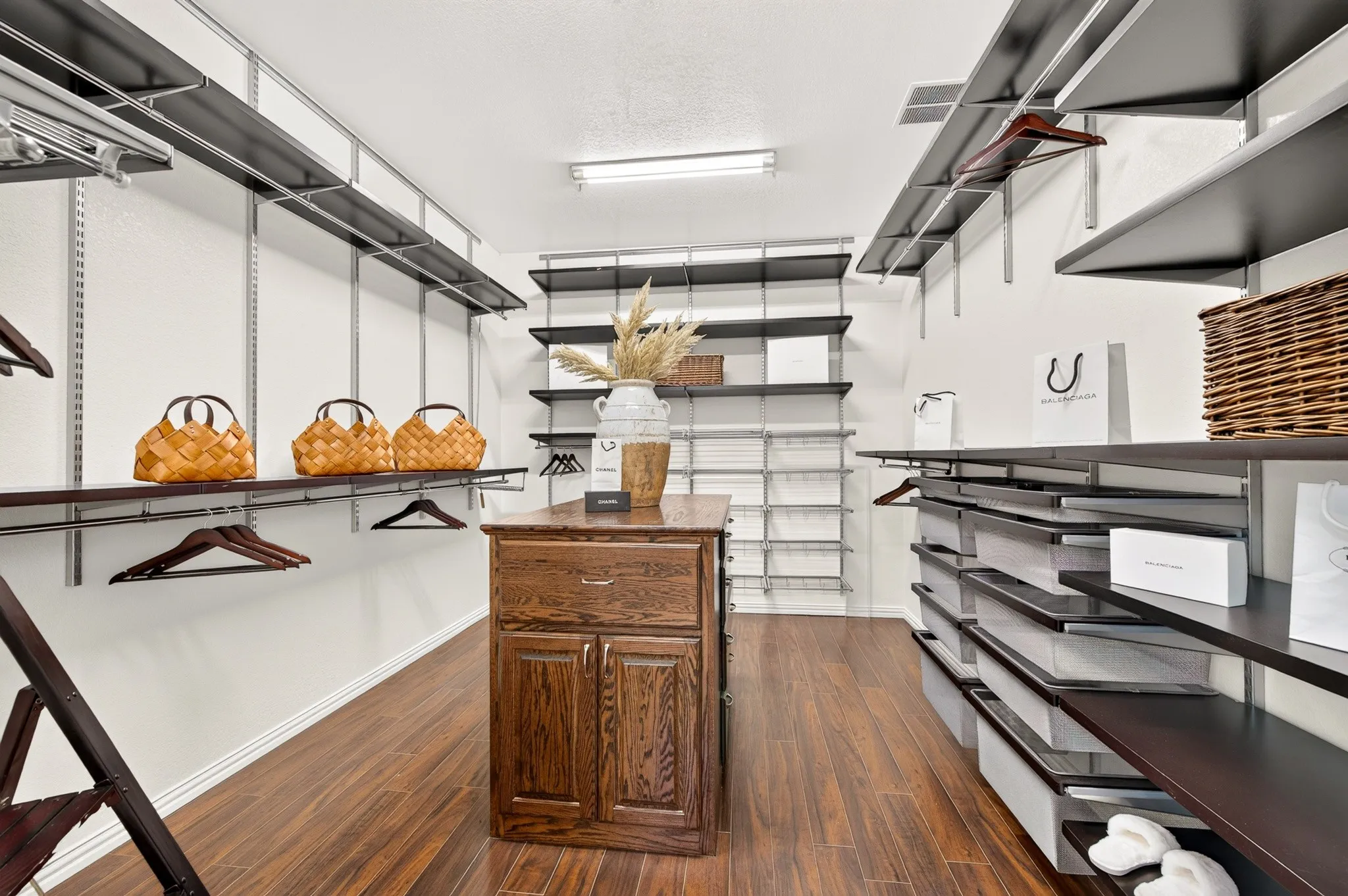 Expansive closet system featuring wood-finish flooring, a central wood island with storage, adjustable shelving, and integrated hanging rods