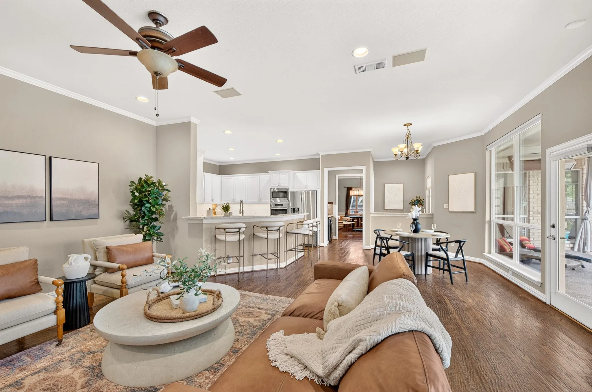Hardwood-finish flooring, recessed lighting, crown molding, a built-in kitchen island with seating, and a dining area with a chandelier