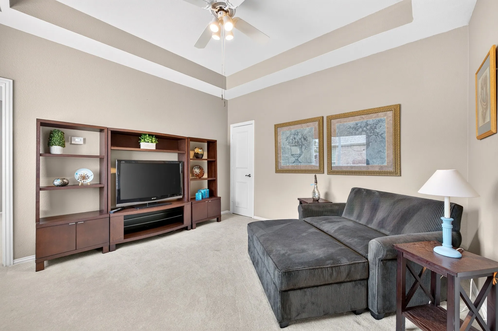Second floor Living-tray ceiling with ceiling fan, neutral wall color, light-toned carpeting