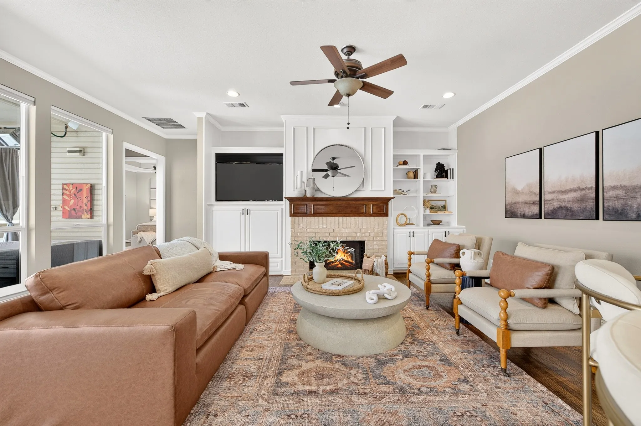 Fireplace with wood mantel, built-in shelving, recessed lighting, ceiling fan, and large windows