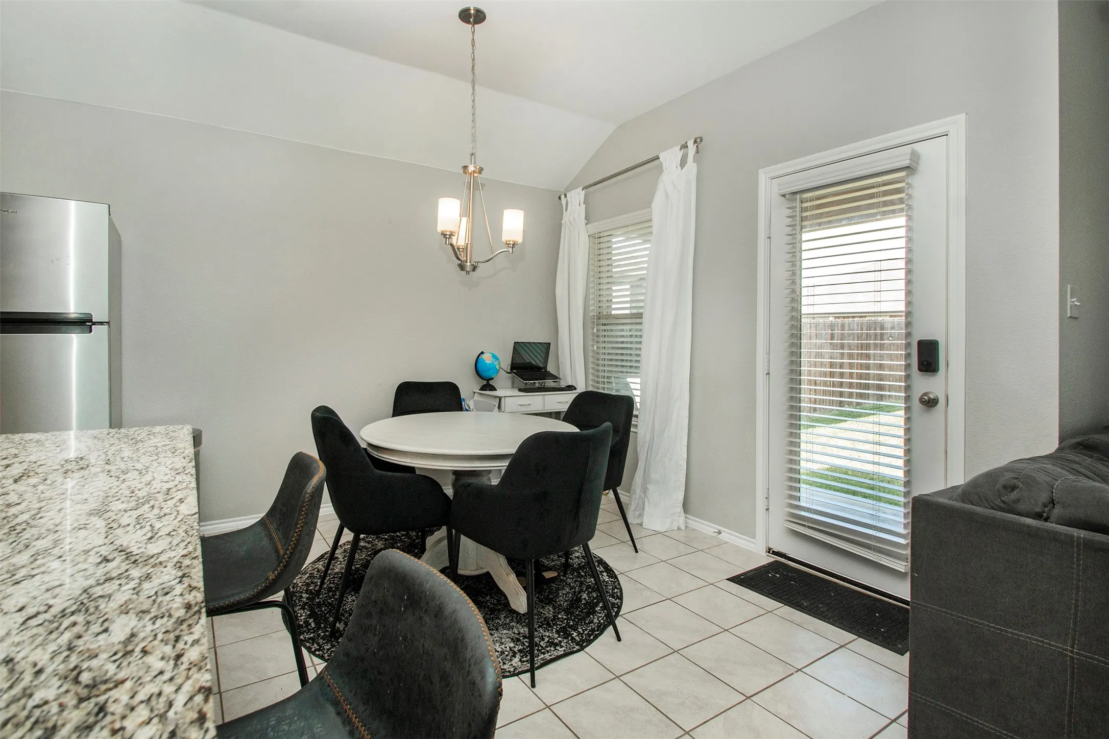 Dining area featuring a contemporary chandelier, tile flooring, and a breakfast bar with a granite-finish countertop