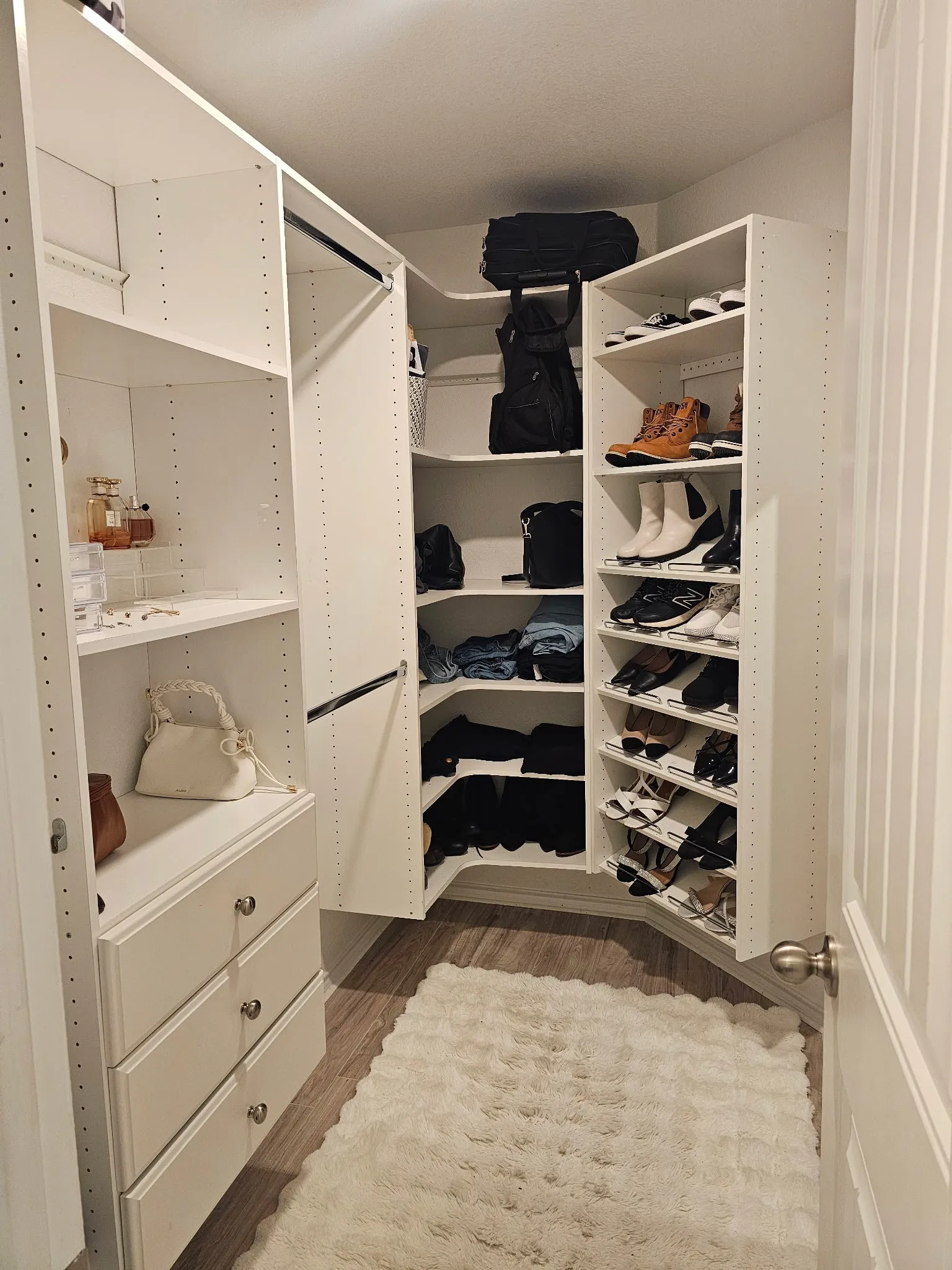 Walk-in closet featuring built-in white cabinetry, integrated shelving, hanging rods, recessed lighting, and wood-finish flooring