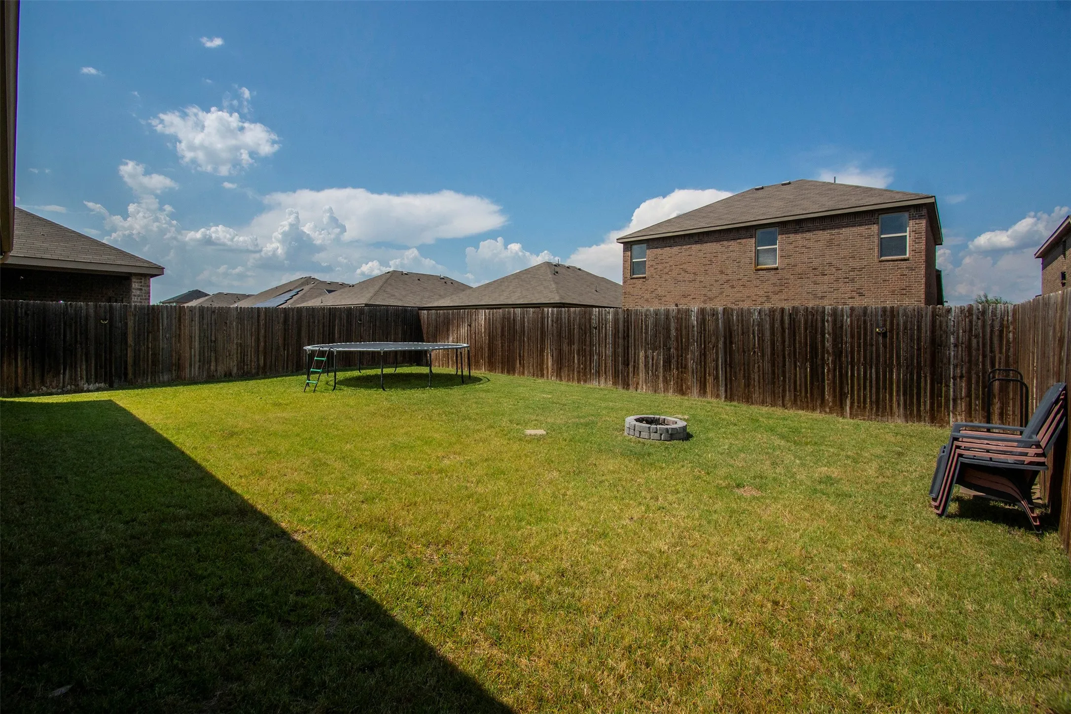 Expansive backyard featuring a manicured lawn, a built-in fire pit, and privacy fencing
