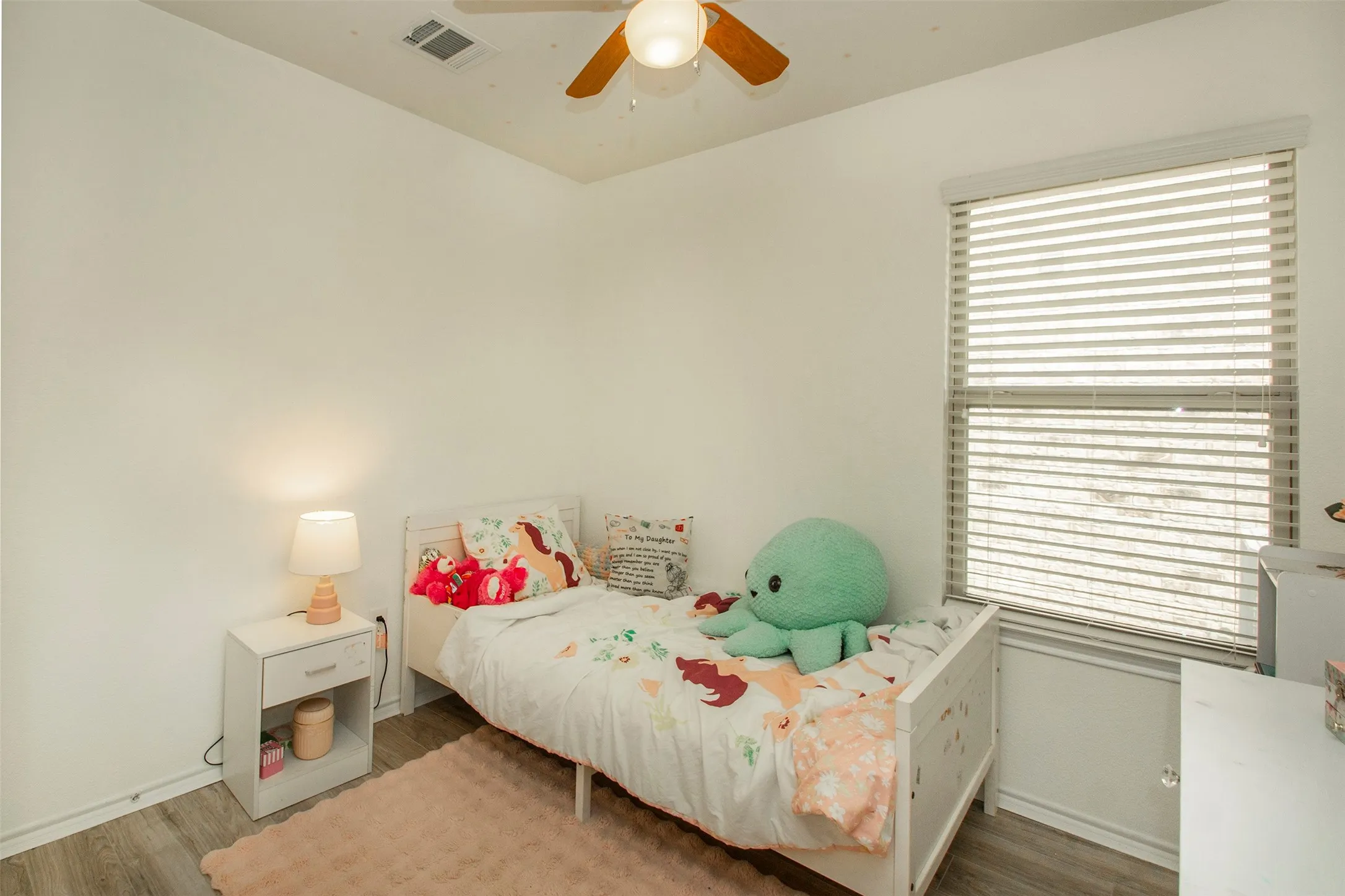 Bright interior space featuring wood-finish flooring, a window with horizontal blinds, and a ceiling fan