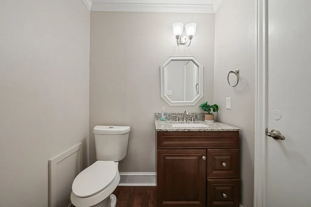 Powder room featuring a dark wood vanity with a light speckled countertop, an undermount sink, and a silver faucet