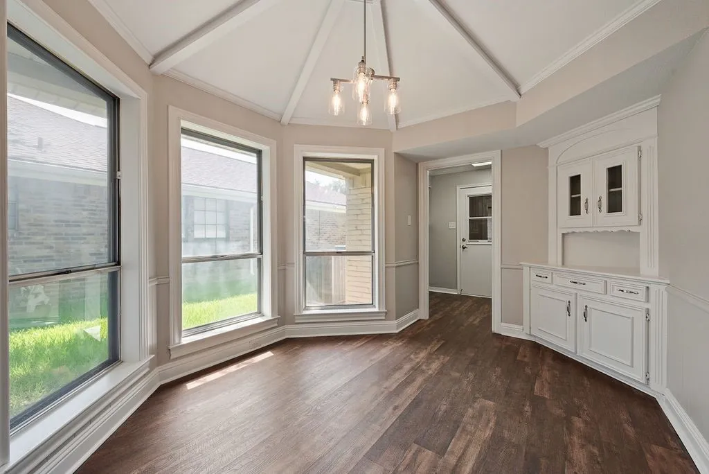 Dining area with wood-finish flooring, a vaulted ceiling, and a contemporary chandelier