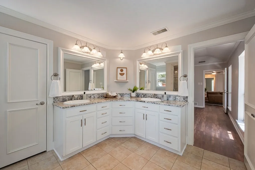 Dual vanity featuring white cabinetry, granite-style countertops, and undermount sinks