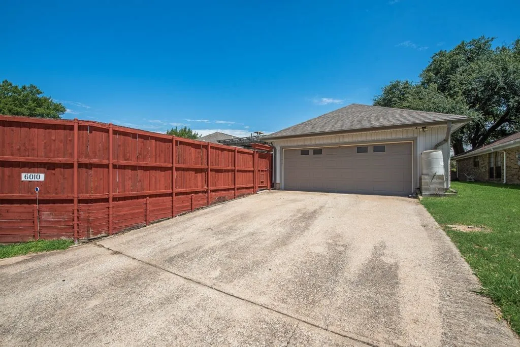 Concrete driveway leading to an attached two-car garage with a paneled door and transom windows