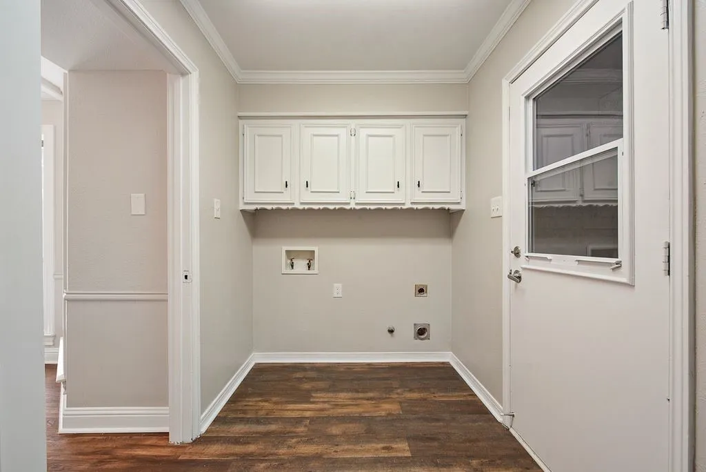 Utility space featuring wood-finish flooring and white overhead cabinetry