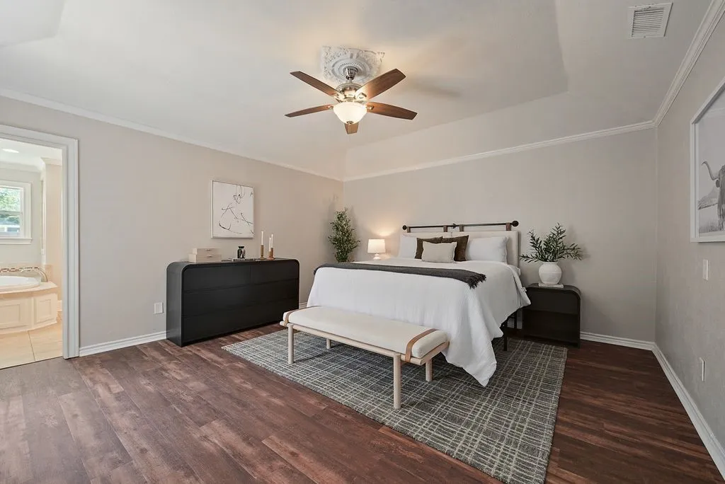 Spacious room featuring wood-finish flooring, a tray ceiling with a decorative medallion, crown molding, and a ceiling fan with integrated lighting