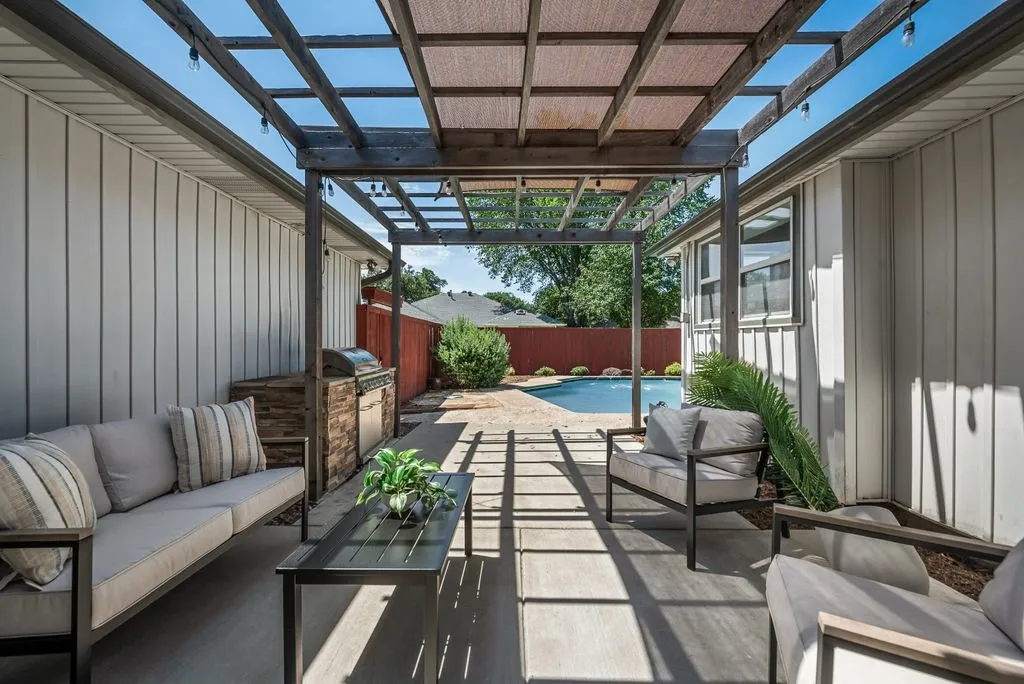 Patio featuring a wood pergola with string lighting, an outdoor built-in grill station with stone-finish cladding, and a concrete surface