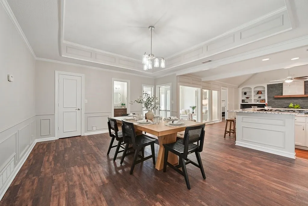 Spacious dining area featuring wood-finish flooring, wainscoting, and a decorative tray ceiling