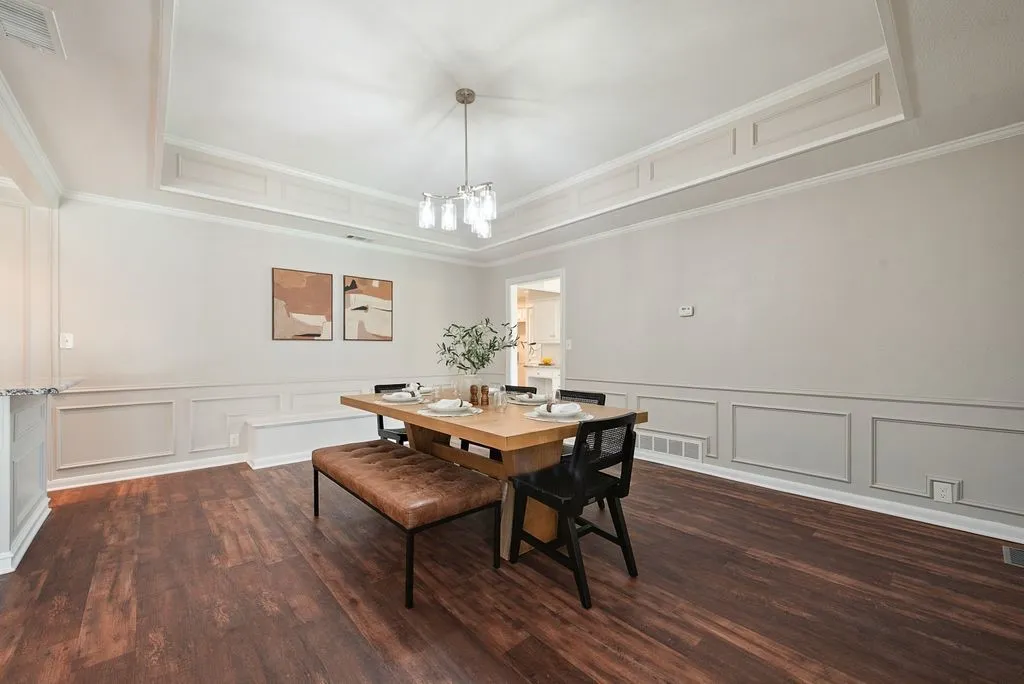 Spacious dining area featuring wood-finish flooring and an elegant tray ceiling