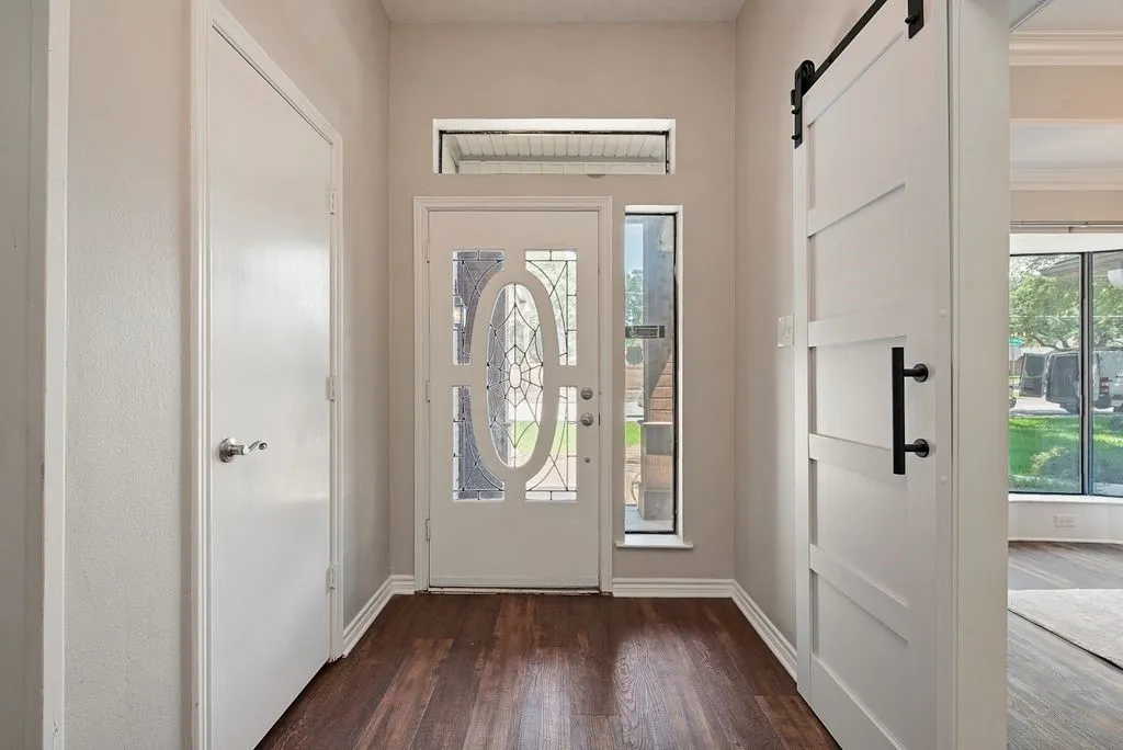 Entryway featuring wood-finish flooring, a white front door with decorative glass, a transom window, and a vertical sidelight