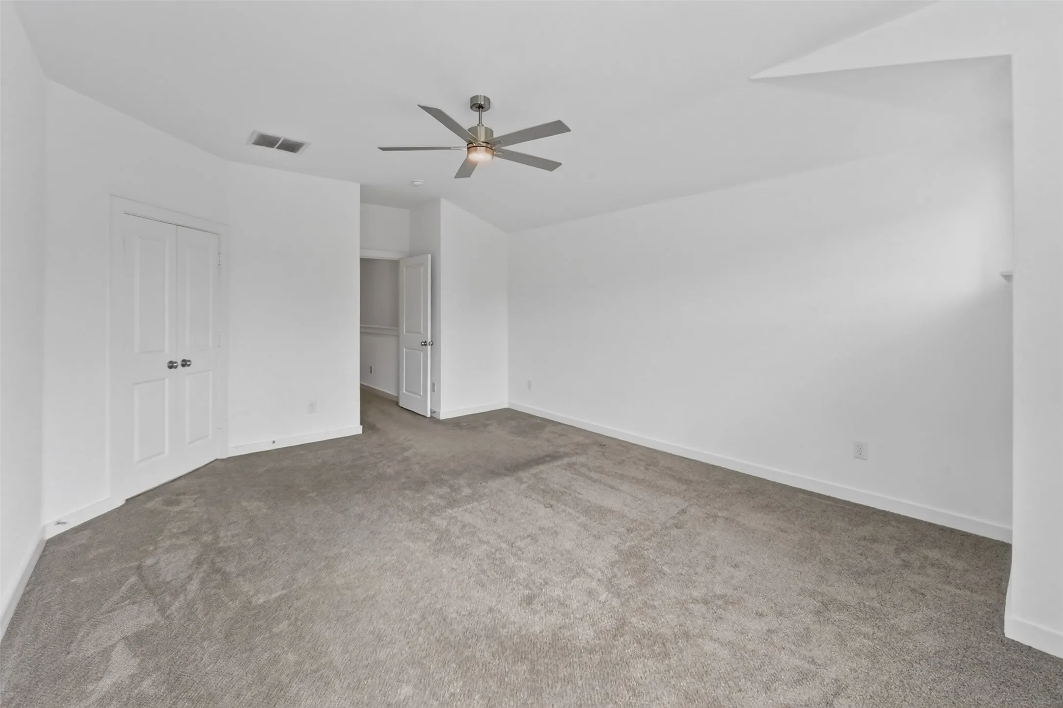 Spacious room featuring neutral carpeting and white walls
