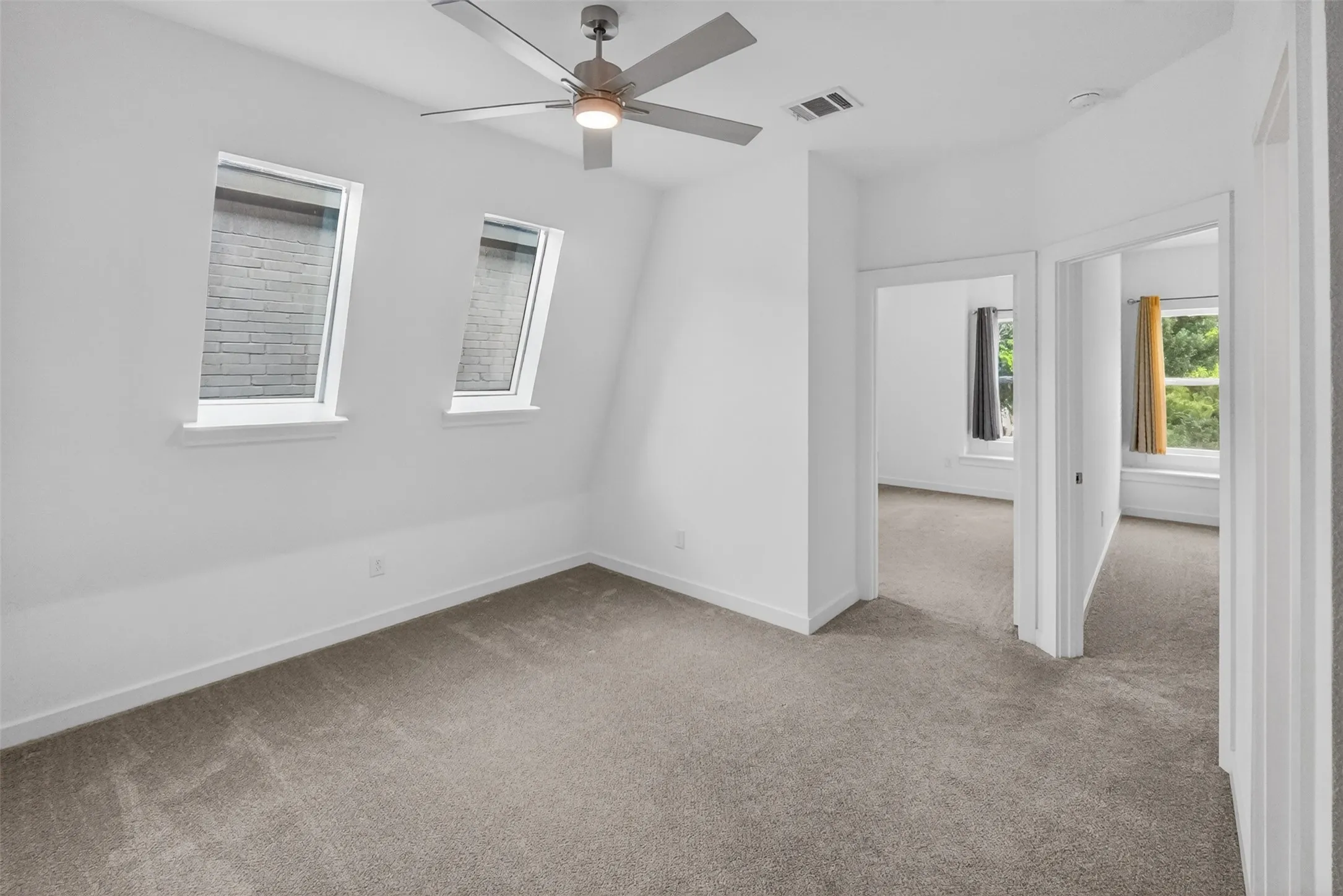 Carpeted room featuring two transom windows, a ceiling fan with integrated lighting, and white trim throughout