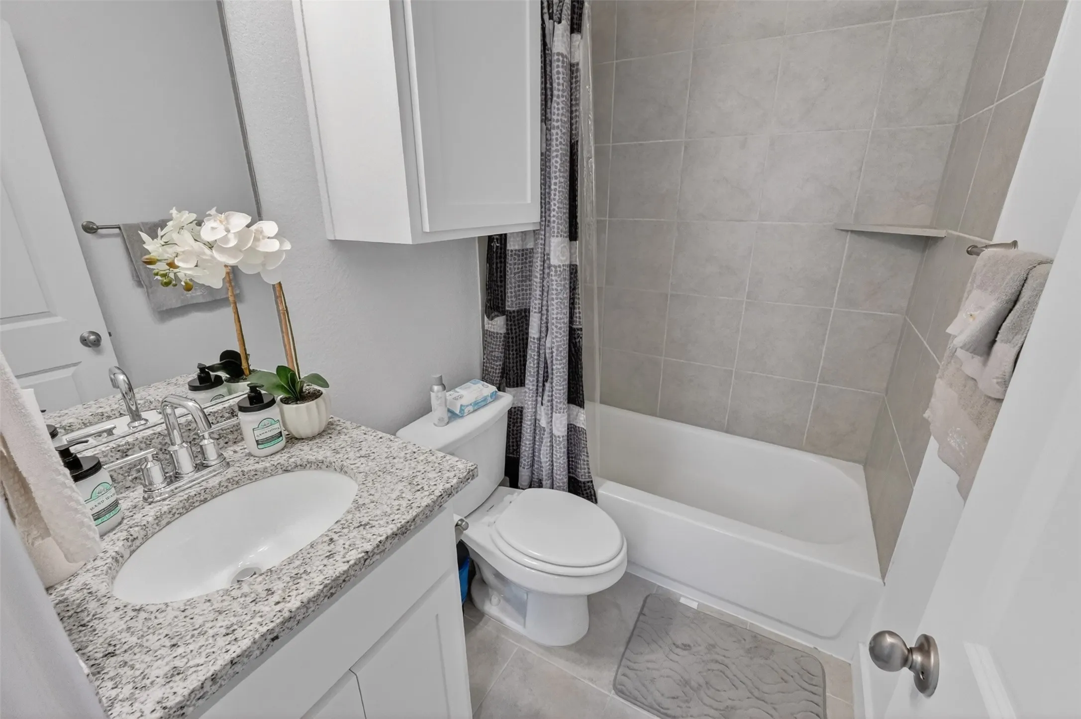 Bathroom featuring a vanity with granite countertop and undermount sink, white cabinetry, and brushed nickel fixtures