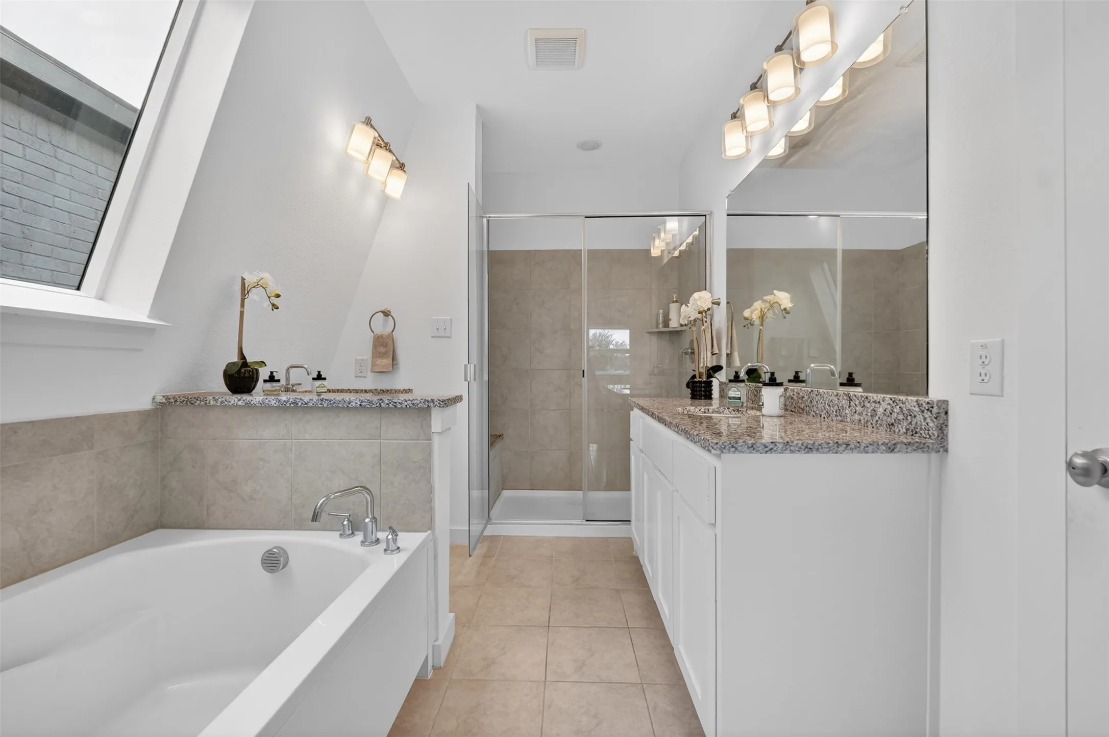 Bathroom featuring a built-in soaking tub, a dual vanity with granite countertop, and a tiled shower with glass enclosure