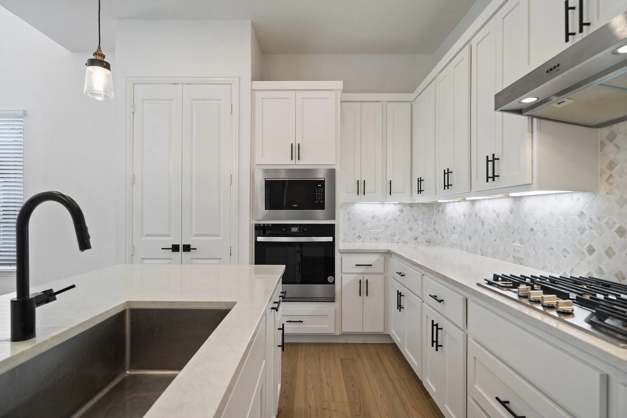 Modern kitchen featuring white shaker cabinetry, stainless steel appliances, a gas cooktop, and a mosaic tile backsplash