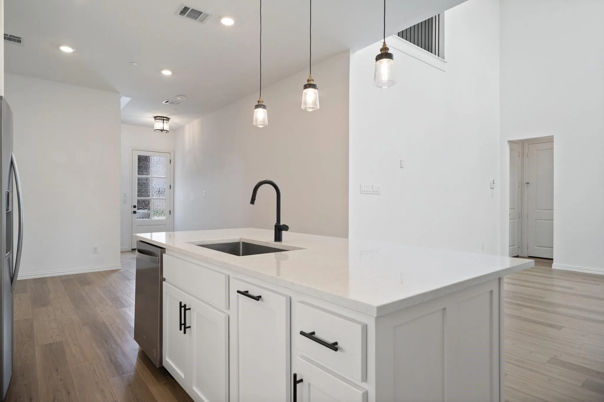 Kitchen island with a white countertop and base cabinetry, featuring a matte black gooseneck faucet and a stainless steel sink