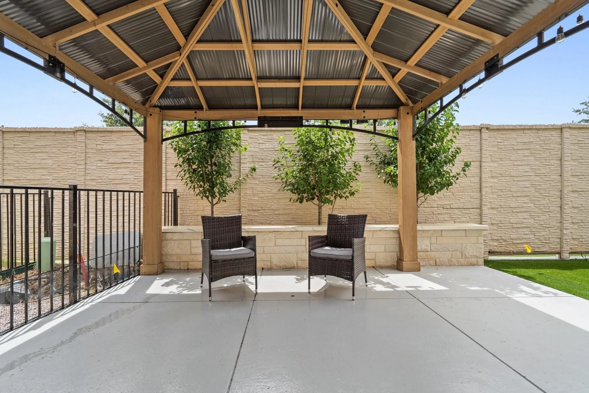 Covered patio featuring a corrugated metal roof, wood-finish beams, and a concrete slab