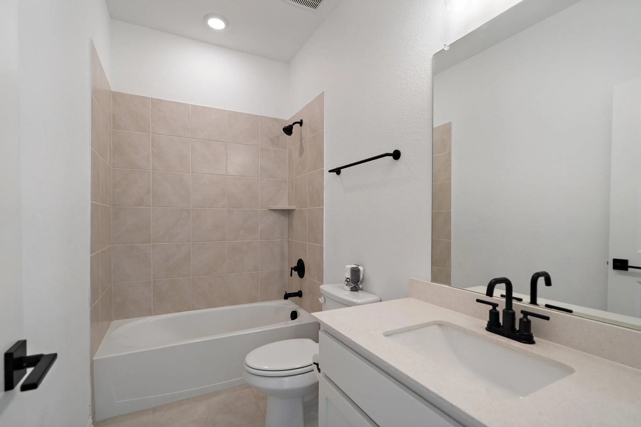 Contemporary bathroom featuring a white vanity with an integrated sink, light-toned countertop, and matte black fixtures