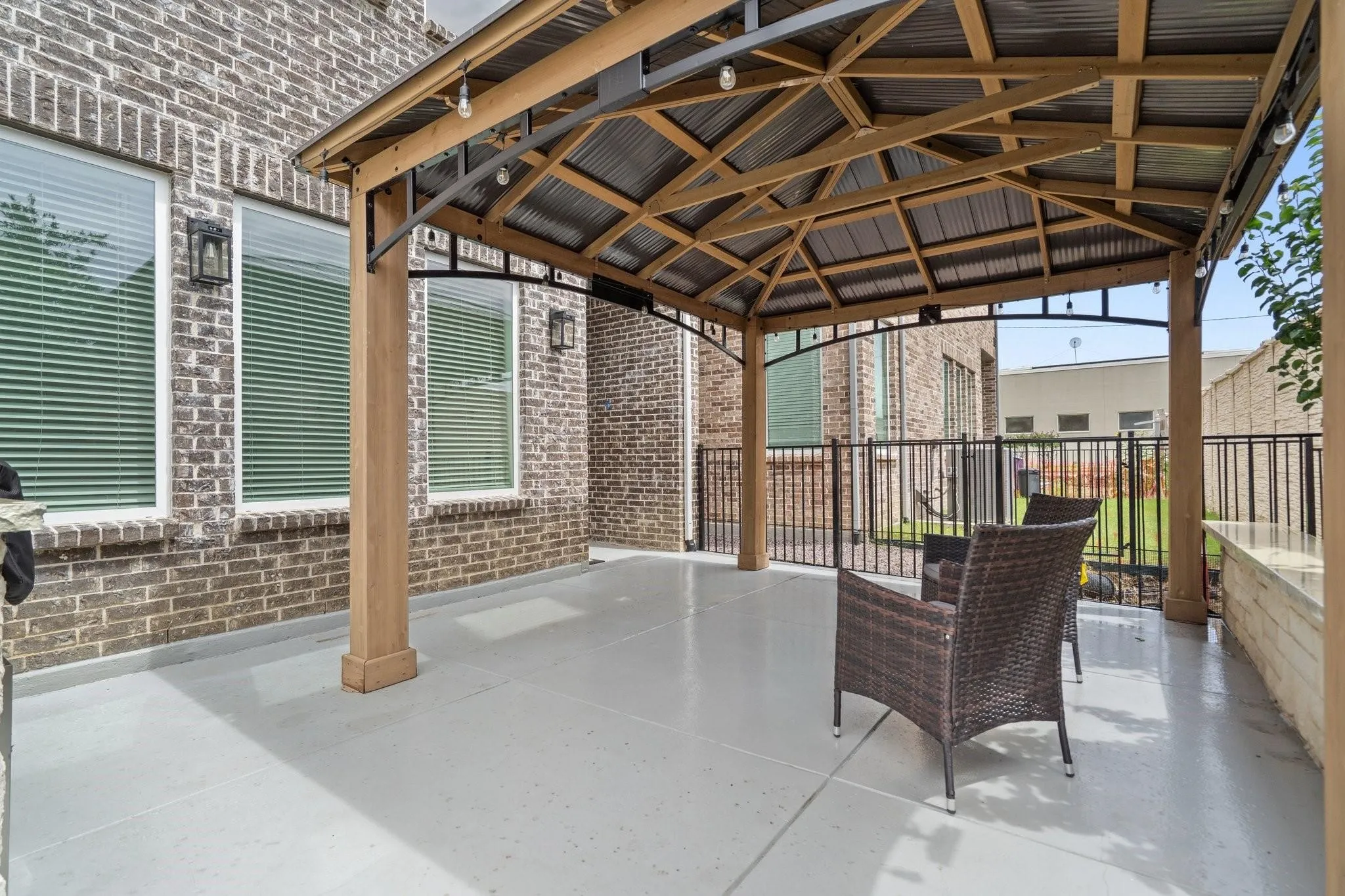 Covered patio featuring a metal roof structure, string lighting, and direct access to a fenced outdoor area
