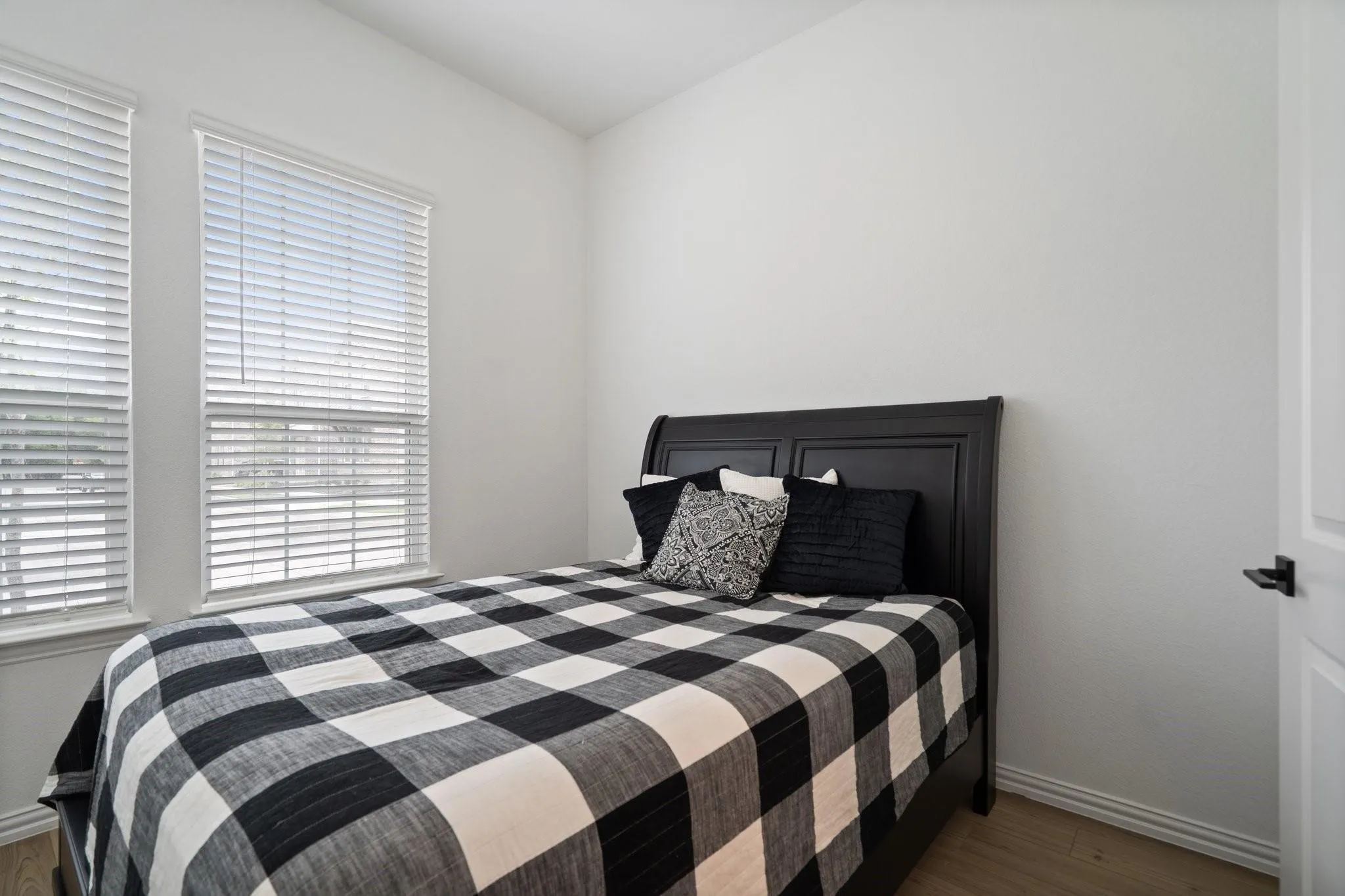 Parents' Bedroom featuring two windows with white blinds, wood-finish flooring, and white baseboards