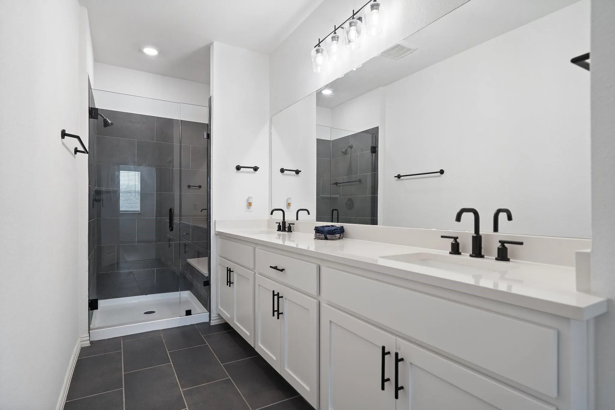 Bathroom featuring a dual vanity with white cabinetry, white countertops, and matte black fixtures