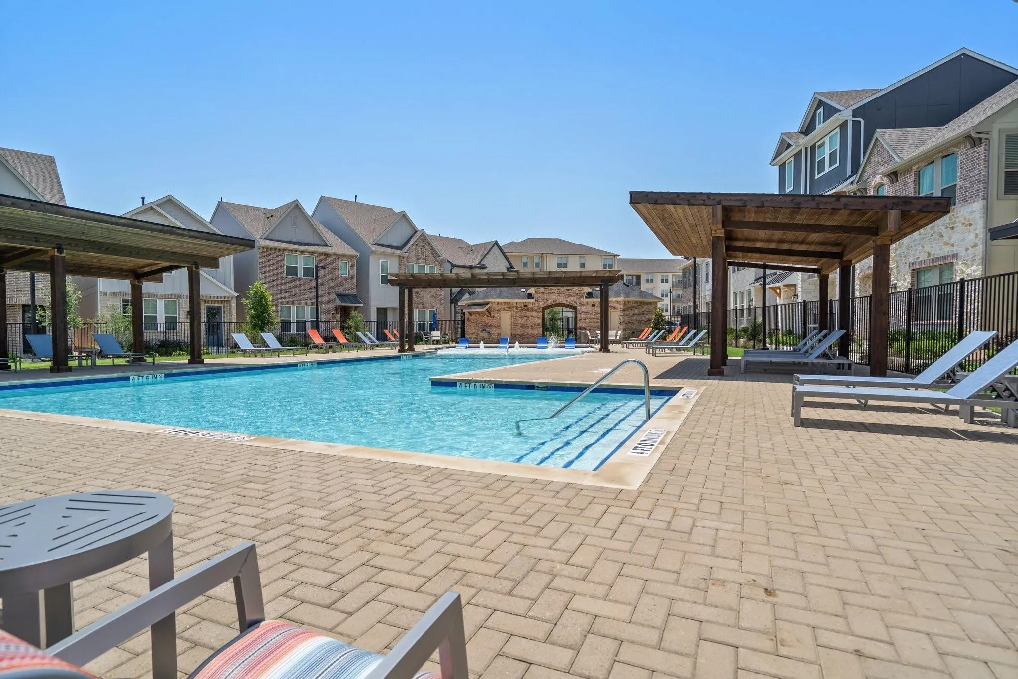 Resort-style community swimming pool with integrated fountains and a spacious surrounding paver patio