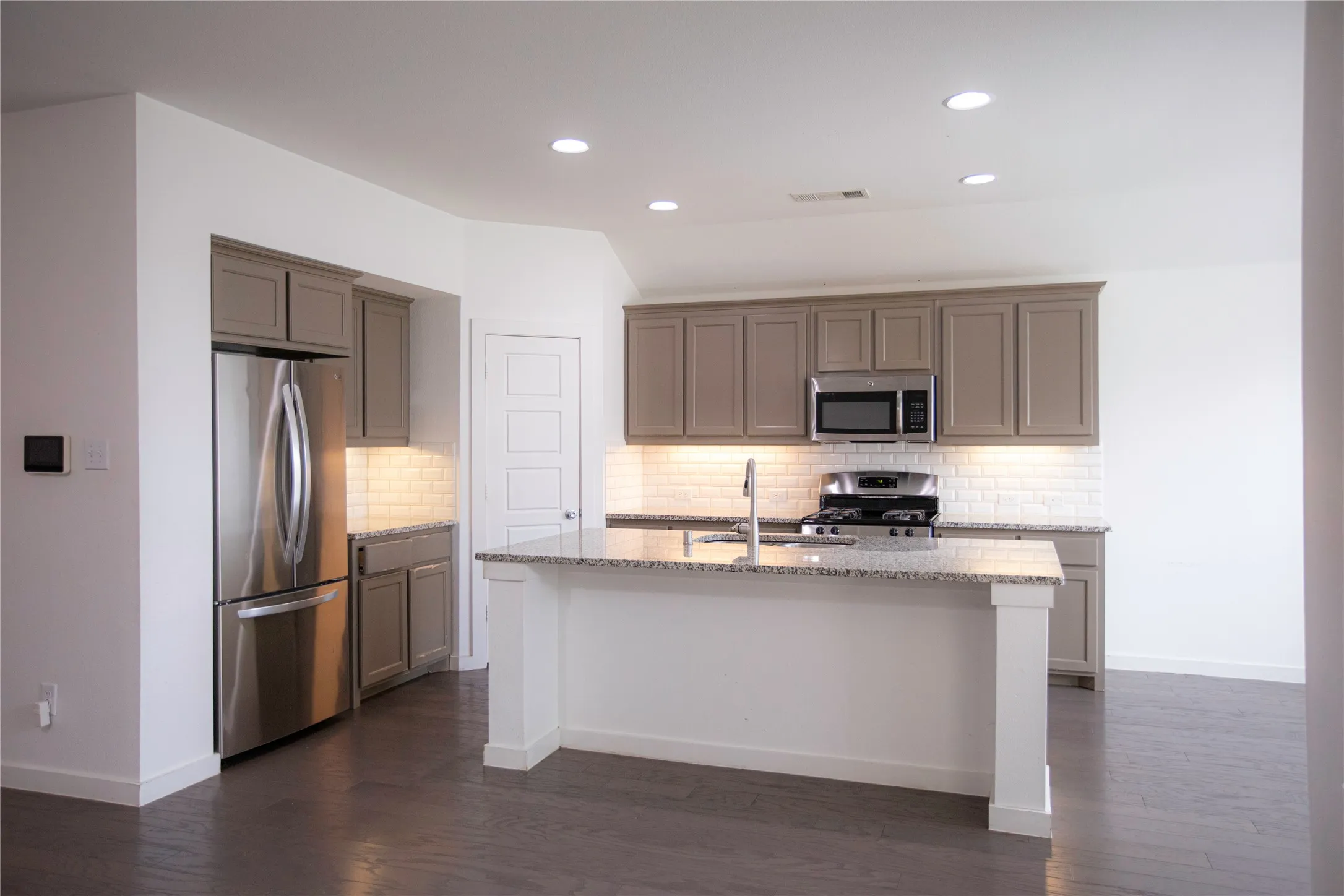 Kitchen featuring a spacious island with granite countertops, stainless steel appliances, subway tile backsplash, and recessed lighting