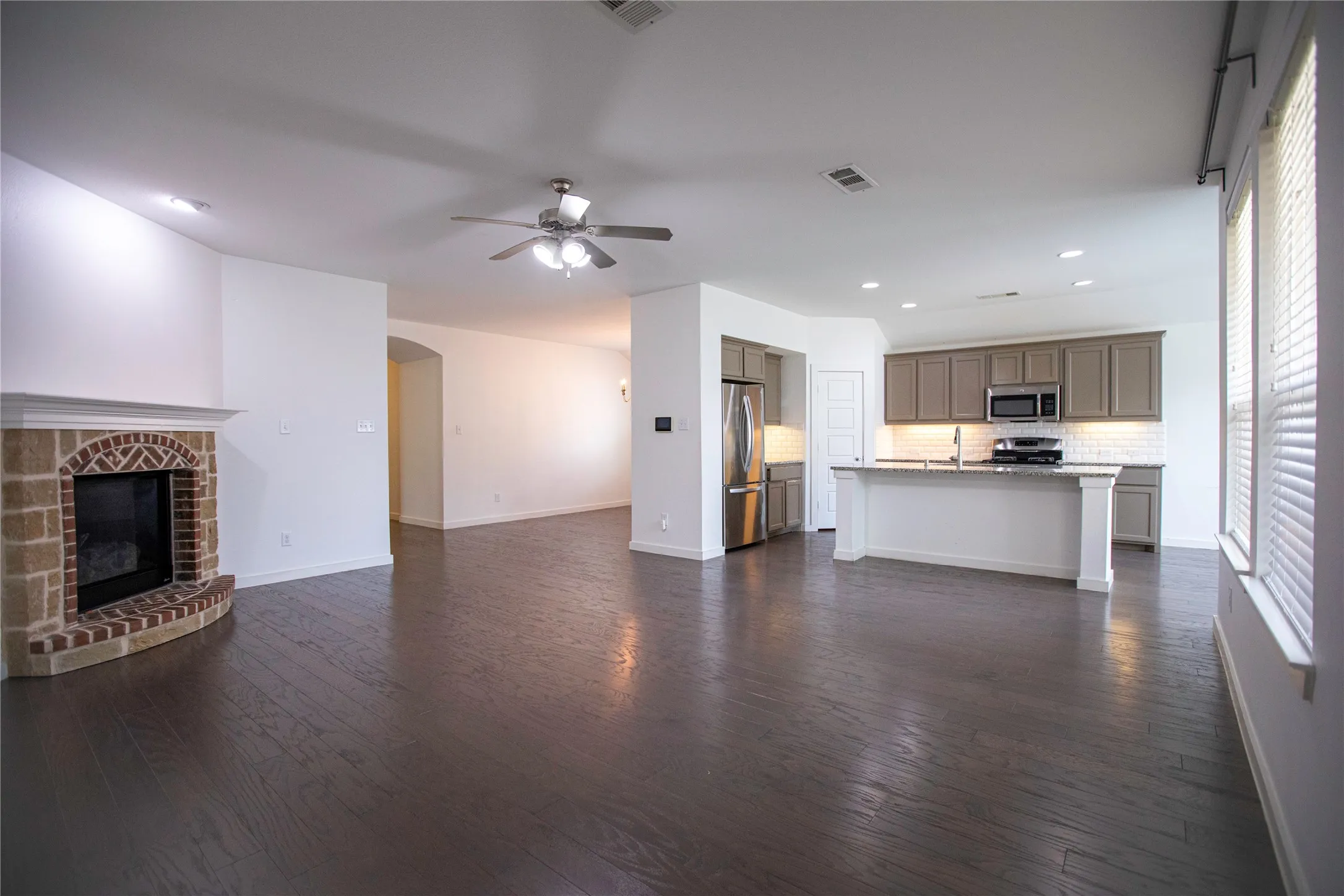 Spacious living area featuring a brick fireplace, wood-finish flooring, and recessed lighting