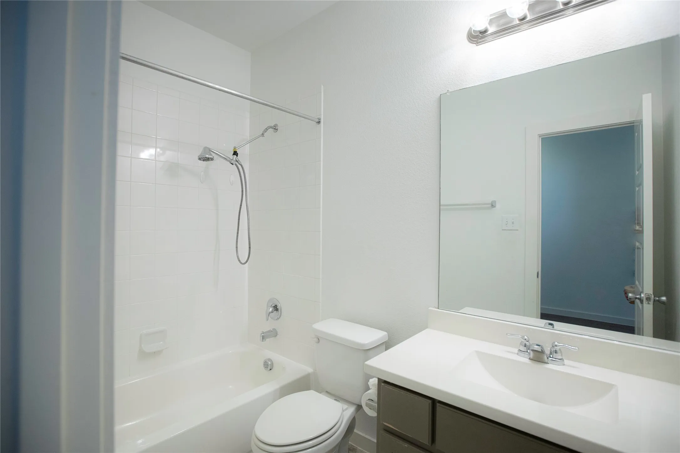 White ceramic tile shower surround with a handheld shower fixture