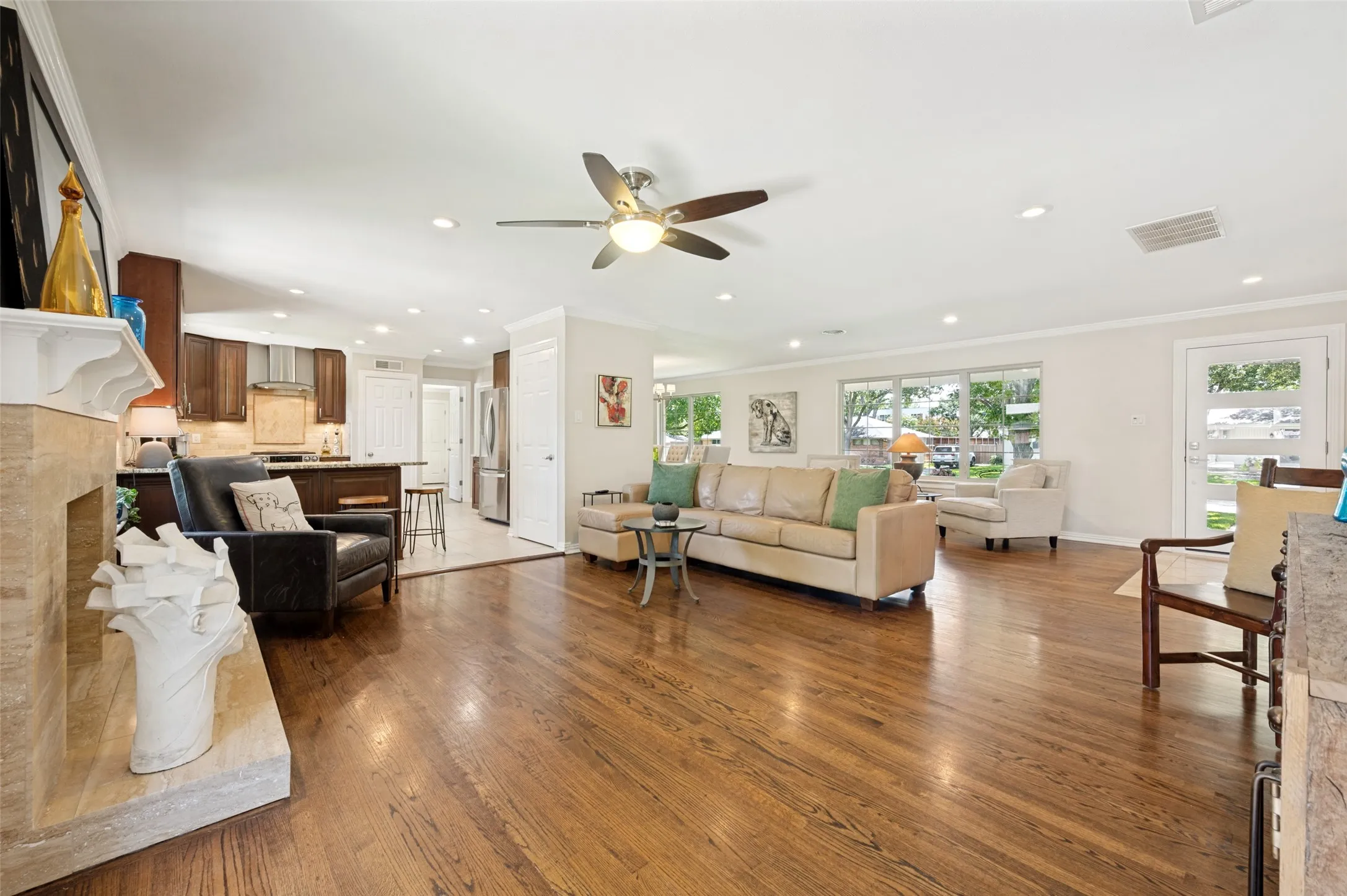 Expansive living area featuring rich wood flooring, a contemporary ceiling fan, and recessed lighting