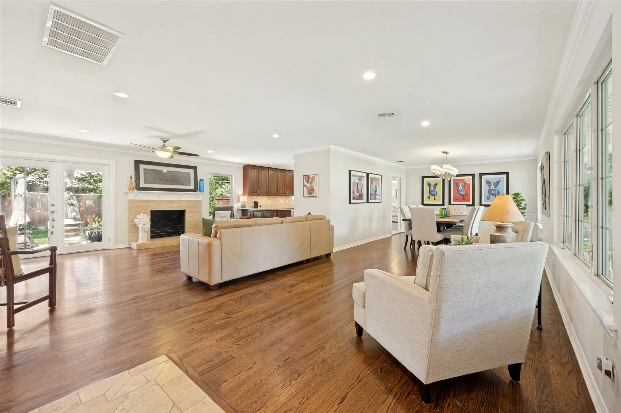Spacious living area featuring rich wood flooring, a stone fireplace, and ample natural light from large windows