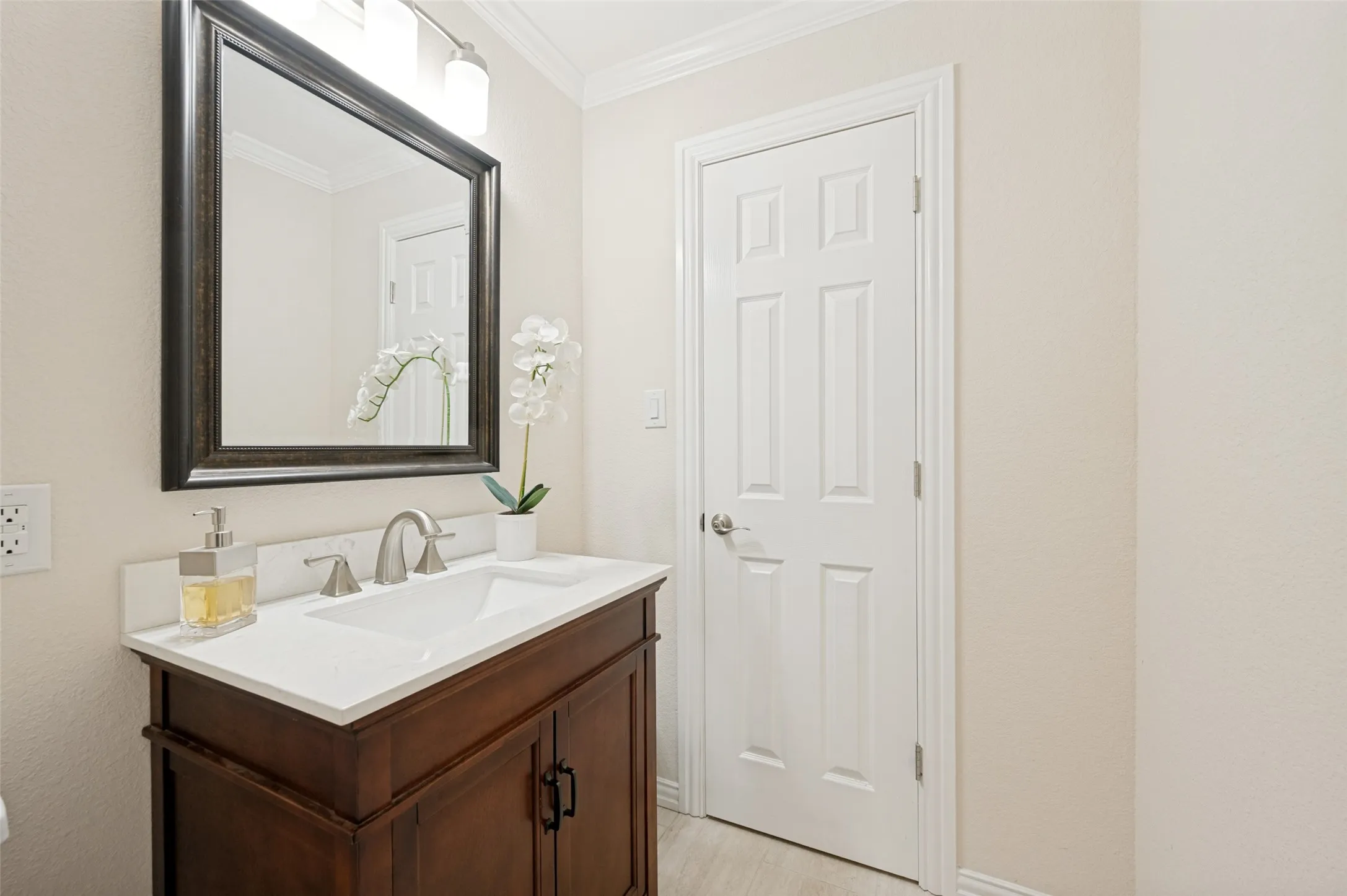 Half bath off the living area with wood vanity with a white countertop and integrated rectangular sink