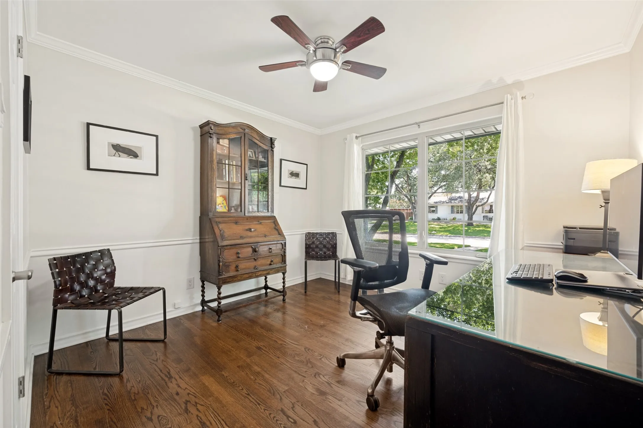 Room with hardwood flooring, wainscoting, crown molding, and a ceiling fan with light fixture