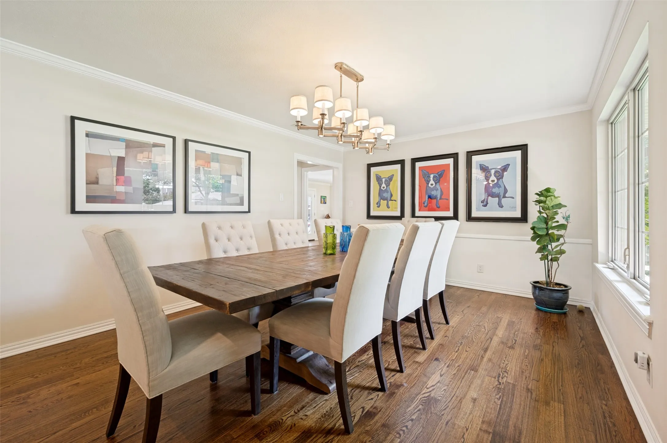 Hardwood flooring extends throughout this room, featuring a chandelier with multiple lights and crown molding