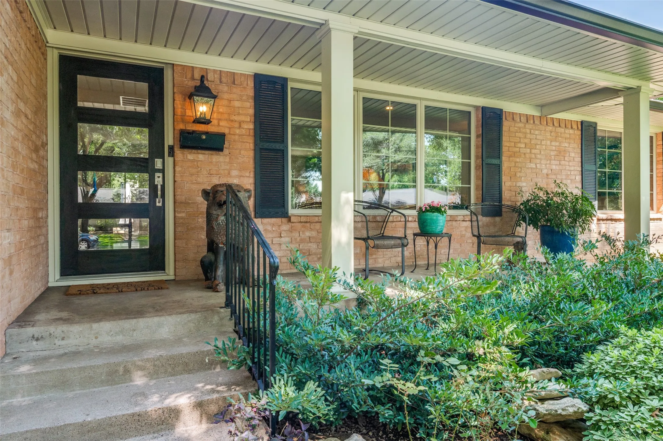 Brick exterior with a covered front porch, featuring a contemporary black entry door with multiple glass panels