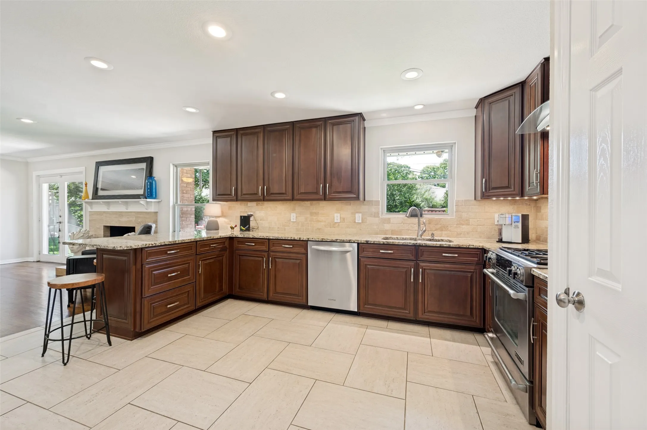 Kitchen featuring an L-shaped counter with rich wood cabinetry, stone-finish countertops, and a tile backsplash